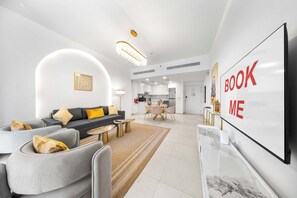 A modern living room with a sofa, coffee table, and TV. There is a kitchen in the background. - Stayshort - Bright 1 Bedroom in Madinat Jumeirah Living That Sleeps 2 With Balcony (Dubai)