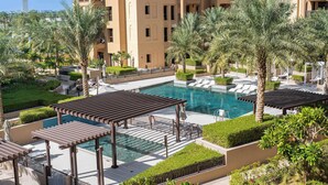 Ein Poolbereich eines Resorts mit Palmen, Liegestühlen und einer Pergola.
