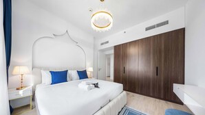 Ein modernes Hotelzimmer mit einem großen Bett, einem Holzschrank, einem Nachttisch mit Lampe und einem blauen Akzentteppich.
