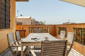 A wooden table with chairs on a balcony, overlooking a cityscape. - Penthouse with stunning TERRACE / Arco de Triunfo (08009 Barcelona)