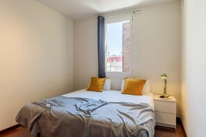 A bedroom with a bed, pillows, a nightstand, a lamp, and a window. - Penthouse with stunning TERRACE / Arco de Triunfo (08009 Barcelona)