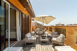 A rooftop terrace with a wooden deck, outdoor furniture, and a large umbrella. - Penthouse with stunning TERRACE / Arco de Triunfo (08009 Barcelona)