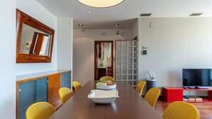 A modern dining area with a long table, yellow chairs, a central white bowl, and a red entertainment unit. - Penthouse with stunning TERRACE / Arco de Triunfo (08009 Barcelona)