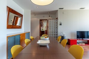 A modern dining area with a long table, yellow chairs, a central white bowl, and a red entertainment unit. - Penthouse with stunning TERRACE / Arco de Triunfo (08009 Barcelona)