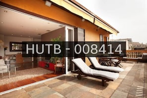 A modern hotel exterior with a glass door entrance, lounge chairs, and a patio area. - Penthouse with stunning TERRACE / Arco de Triunfo (08009 Barcelona)
