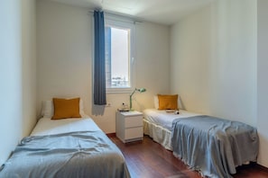Un dormitorio con dos camas, una mesita de noche, una lámpara y una ventana con vistas.