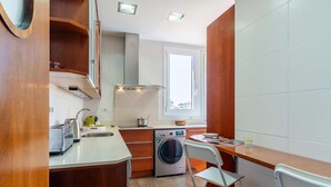 A compact kitchen with a washing machine, a sink, a toaster, and a window providing natural light. - Penthouse with stunning TERRACE / Arco de Triunfo (08009 Barcelona)
