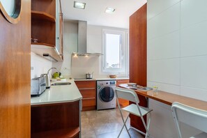 A compact kitchen with a washing machine, a sink, a toaster, and a window providing natural light. - Penthouse with stunning TERRACE / Arco de Triunfo (08009 Barcelona)