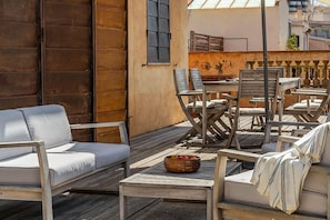 Un espacio al aire libre con mesa de madera, sillas y un sofá.