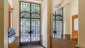 A hallway with a large black gate, a tiled floor, and a wall-mounted light fixture. - Penthouse with stunning TERRACE / Arco de Triunfo (08009 Barcelona)