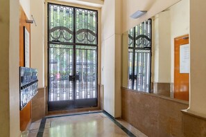 A hallway with a large black gate, a tiled floor, and a wall-mounted light fixture. - Penthouse with stunning TERRACE / Arco de Triunfo (08009 Barcelona)