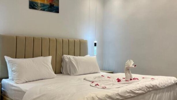 A neatly made bed with white linens, a decorative swan figure, and rose petals arranged on the bed. - Spacious King Room with Mountain View Near the Giza Pyramids (Nazlat as Sammān)