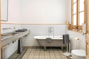 Een badkamer met een bad, wastafel en toilet.