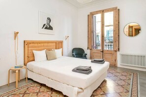 A bedroom with a wooden bed, a chair, a radiator, a window with a view, and a framed picture on the wall. - FAMILY FRIENDLY MODERNIST TERRACE APARTMENT (08009 Barcelona)