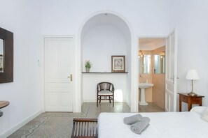 Ein Hotelzimmer mit einem Bett, einem Sessel, einem kleinen Tisch, einem Waschbecken und einem Spiegel.