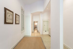 Un couloir avec des tableaux encadrés accrochés au mur, un sol recouvert de moquette et une porte donnant sur une autre pièce.