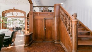 Een statige trap met houten spijlen en een leuning, die uitkomt op een plateau met dubbele deuren.