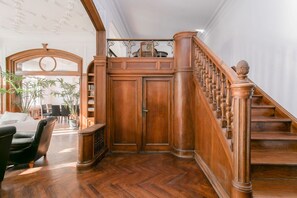 Eine prächtige Treppe mit hölzernen Balustern und einem Geländer, die zu einer Empfangshalle mit Doppeltüren führt.