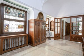 Un hall d’entrée spacieux, avec un radiateur, un meuble en bois et un vélo.