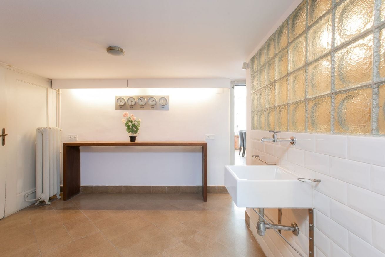Un bagno con un lavandino bianco, uno specchio e un orologio appeso al muro.