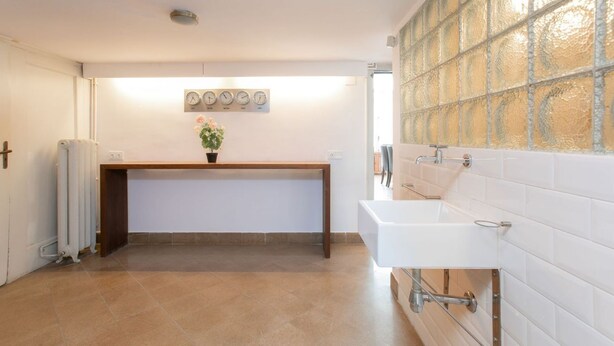 Een badkamer met een wit wastafelmeubel, een spiegel en een klok aan de muur.