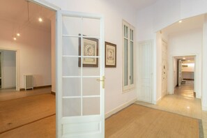 A hallway with a white door, framed pictures on the wall, and a radiator. - Unique & Stylish Townhouse / Paseo de Gracia (08037 Barcelona)