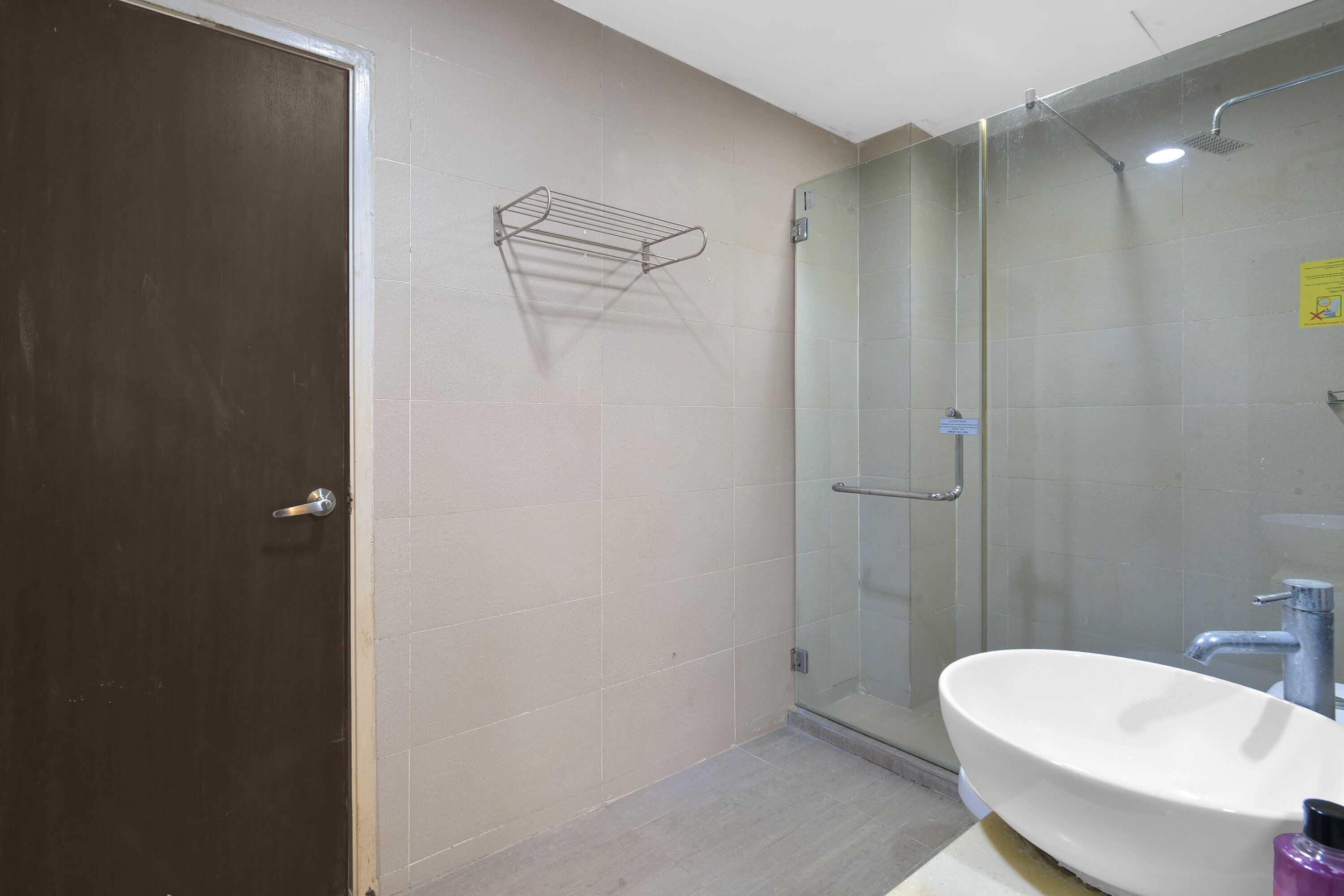 A bathroom with a glass shower enclosure, a white sink, and a towel rack.