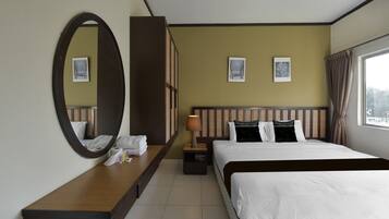 Un cuarto de hotel con una cama grande, una mesita de noche con lámpara, un espejo y dos cuadros en la pared.