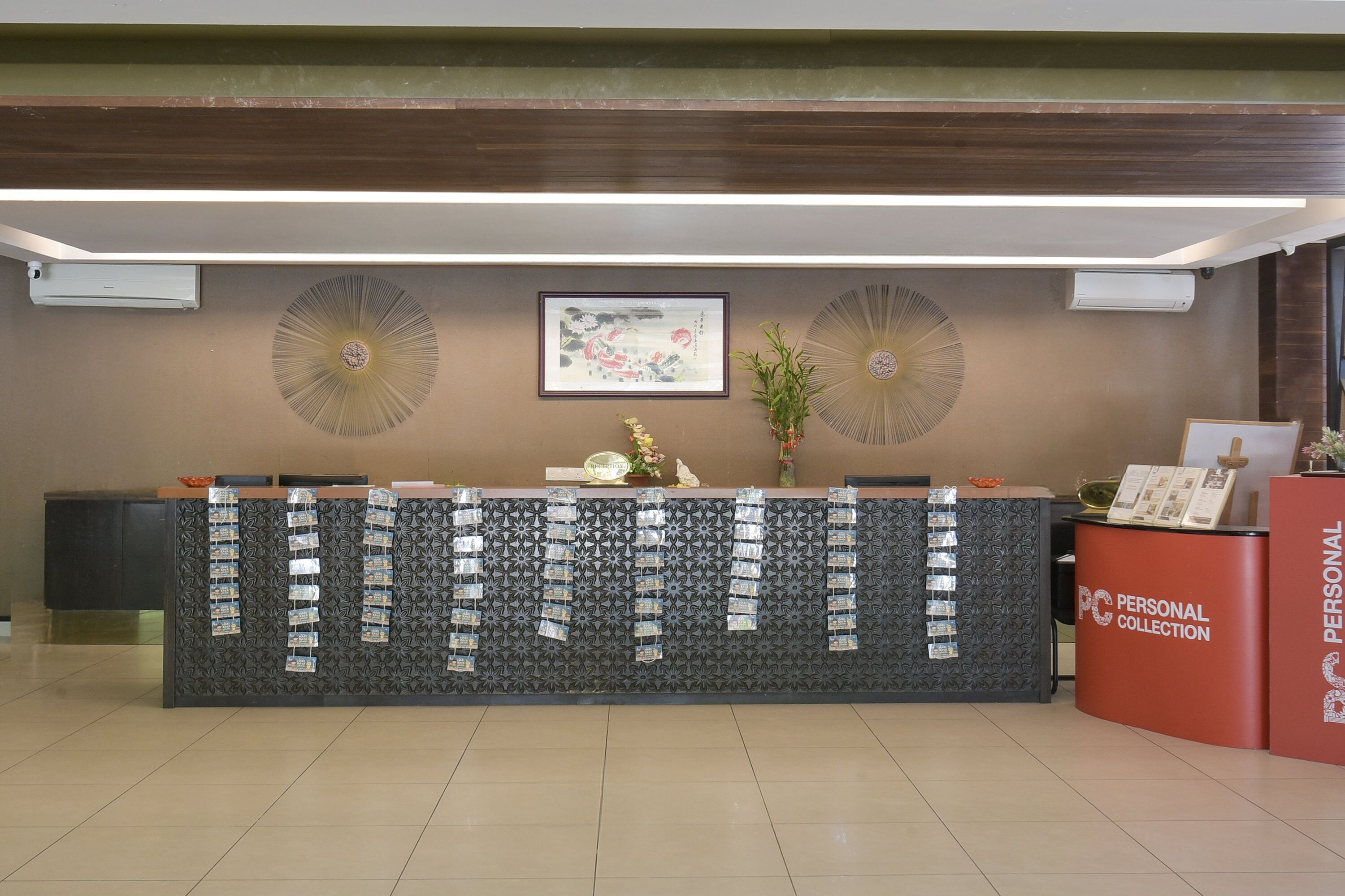 A reception desk with a patterned backdrop, framed artwork, and a red 'PERSONAL COLLECTION' counter.