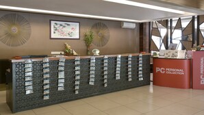 A reception desk with a PC Personal Collection sign, decorative wall art, and a patterned wall. -  Palette - Gold Coast Morib Resort (Banting)