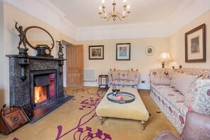 A living room with a fireplace, a sofa, a coffee table, and framed pictures on the wall. - Danes Court, Cartmel Fell (Cartmel Fell)
