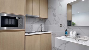 Una cocina moderna con microondas integrado, pileta de acero inoxidable y armarios de madera.