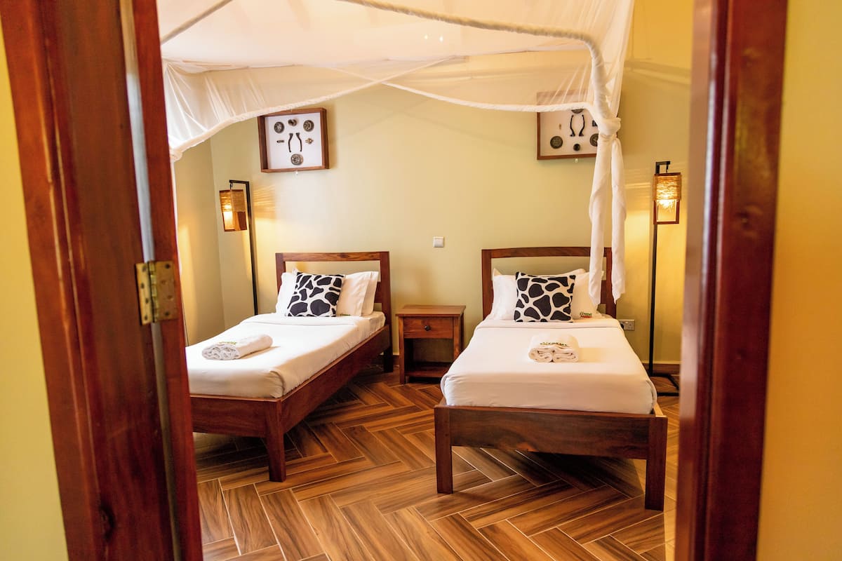 Una habitación con dos camas de madera, cada una con dosel, ropa de cama blanca y una mesita de noche.