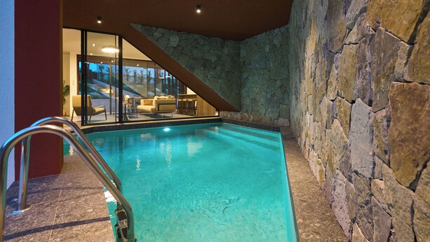 En inomhuspool med väggar av sten och en modern inredning.