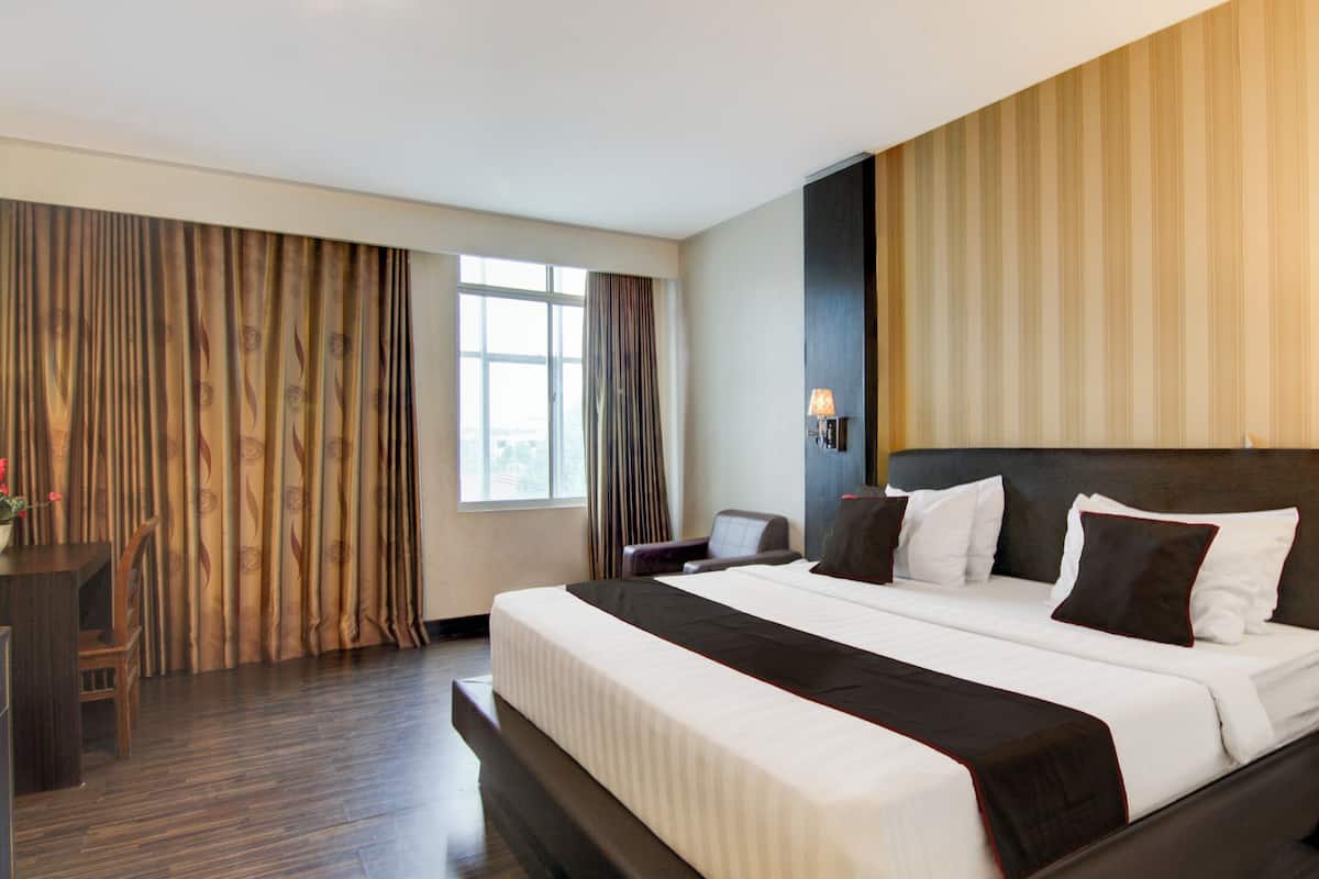 Ein Hotelzimmer mit einem großen Bett, einem Schreibtisch und einem Sessel.