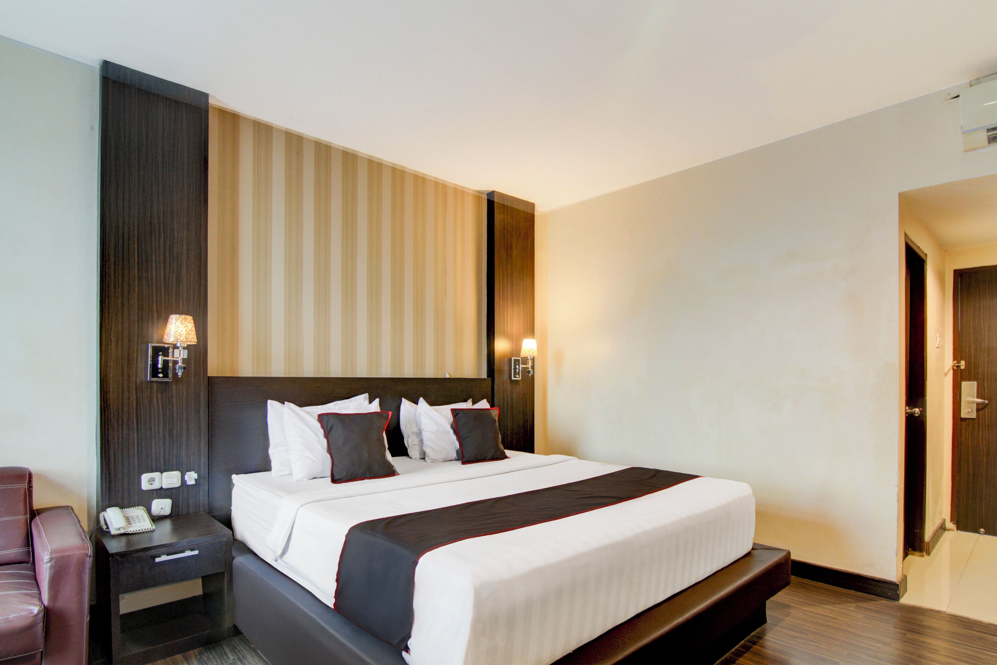 Ein Hotelzimmer mit einem großen Bett, Nachttischen, einer Nachttischlampe und einer Wandlampe.