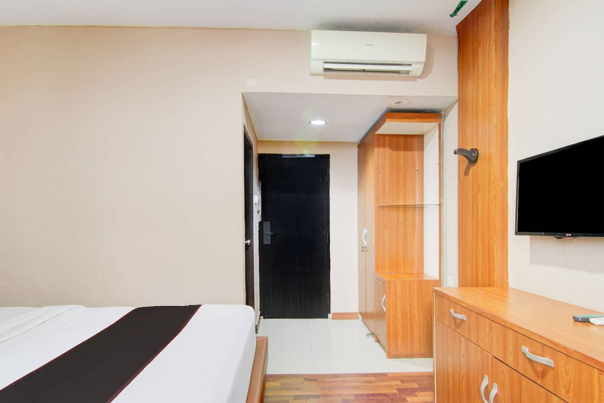 Ein Hotelzimmer mit einem Bett, einem Kleiderschrank, einem Fernseher und einer Klimaanlage.