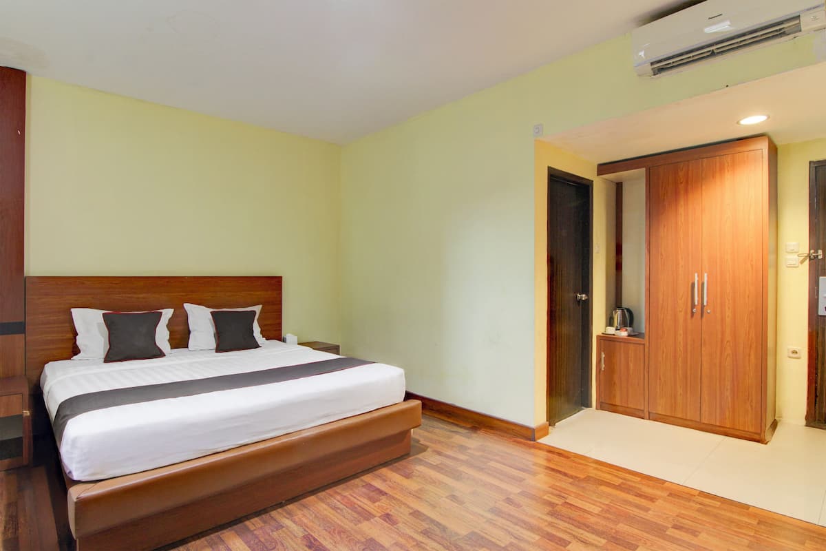 Ein Schlafzimmer mit einem Bett, einem Holzschrank und einer Klimaanlage.