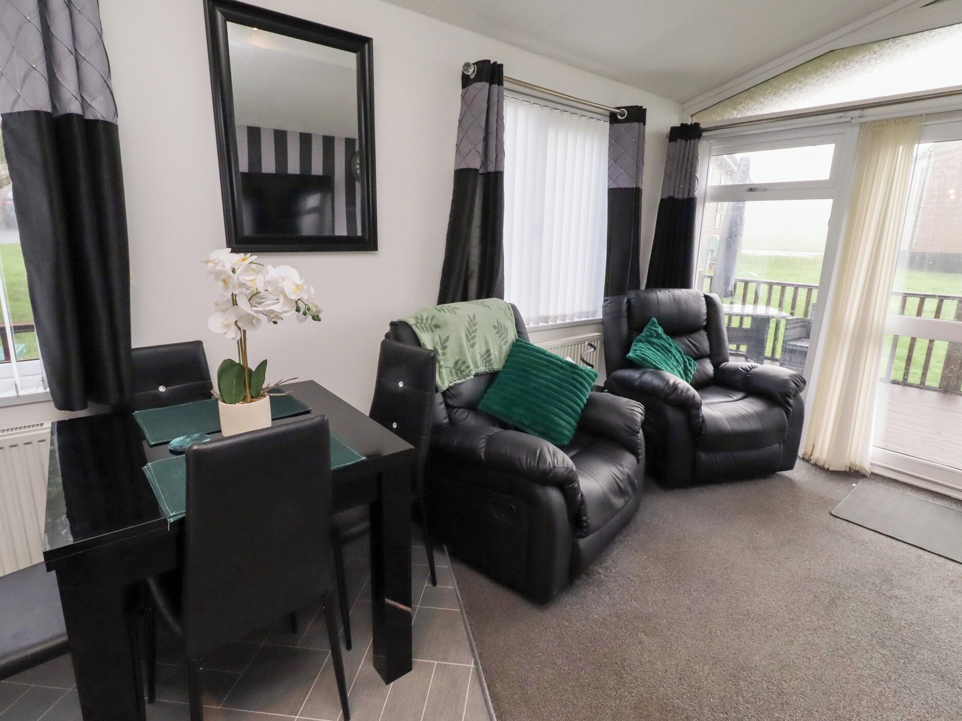 A furnished living room with a dining table, two leather sofas, and a green plant.