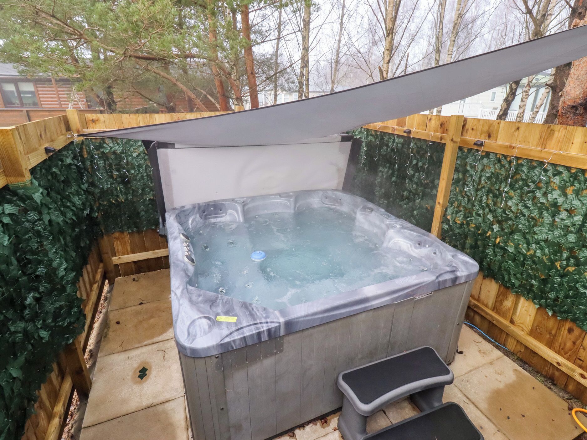 Un jacuzzi con terraza de madera y un escalón para facilitar el acceso.