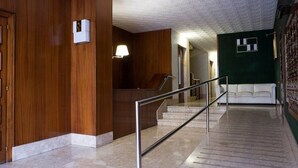 A hotel lobby with a marble staircase, wooden paneling, a white sofa, and a green wall with a window. - Design Flat, Terrace / Paseo de Gracia, Born (Barcelona)