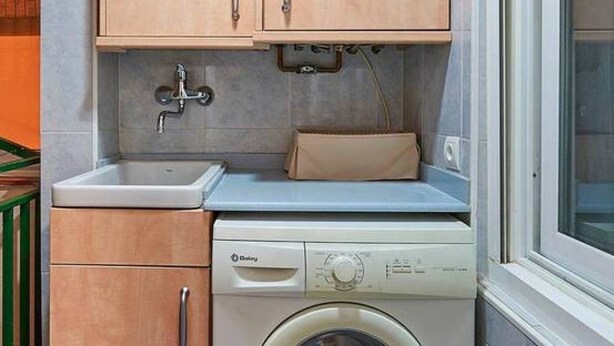 A compact kitchen with a washing machine, a sink, and wooden cabinets. - Design Flat, Terrace / Paseo de Gracia, Born (Barcelona)