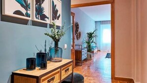 A hallway with a wooden floor, a desk with drawers, a vase with flowers, and framed artwork on the wall. - Design Flat, Terrace / Paseo de Gracia, Born (Barcelona)