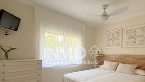 Un dormitorio con cama, cómoda, televisor y decoración en la pared.
