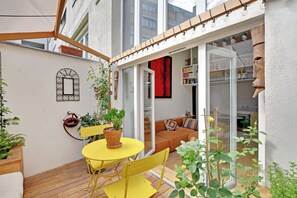 A cozy patio with a yellow table and chairs, a wooden bench, and potted plants. - Beautiful Duplex 1br/2p - Belleville (Paris)
