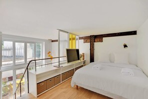 A modern bedroom with a large bed, a TV on a white console, and a balcony with a view. - Beautiful Duplex 1br/2p - Belleville (Paris)