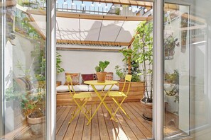 A wooden deck with yellow chairs and a table, surrounded by potted plants and a cushioned bench. - Beautiful Duplex 1br/2p - Belleville (Paris)
