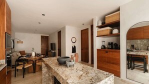 A modern kitchen with a central island, wooden cabinets, and built-in appliances. - Narai Solecito House Tulum Jungle Views Aldea Zama (Tulum)