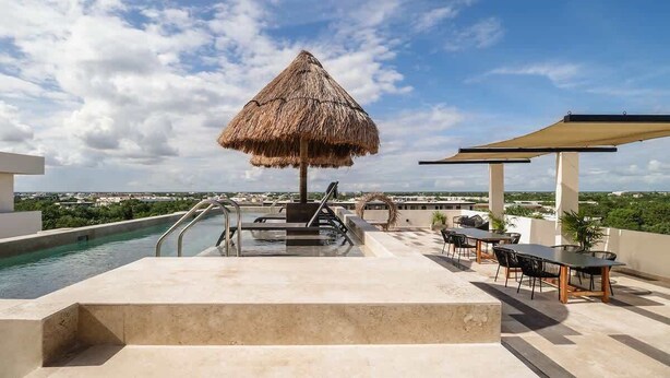 A rooftop pool area with a thatched umbrella, outdoor seating, and a view of the cityscape. - Narai Solecito House Tulum Jungle Views Aldea Zama (Tulum)