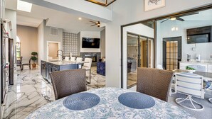 A spacious kitchen with a marble countertop, a dining area with a patterned tablecloth, and a large window overlooking the outdoor area. - Luxe Waterfront Cape Coral Home w/ Gulf Access! (Cape Coral)